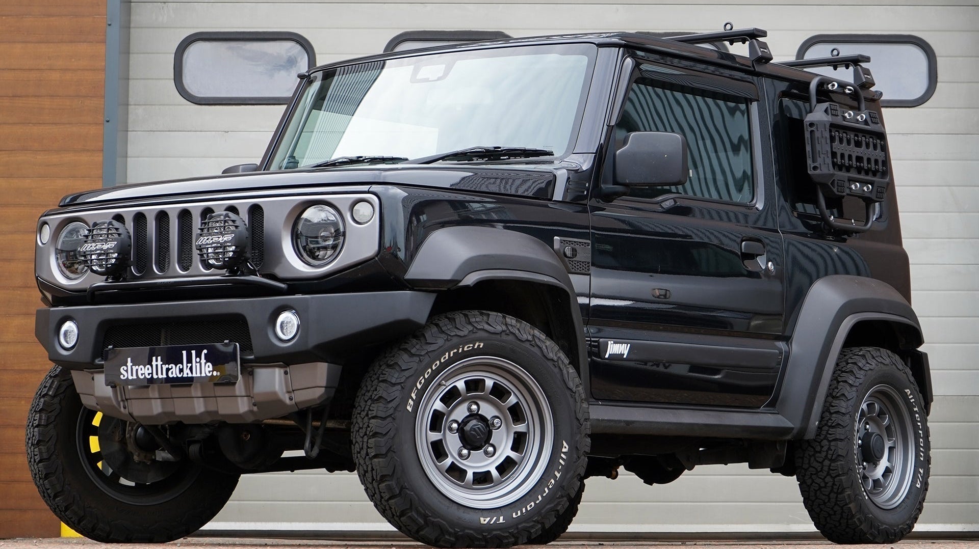 Black Suzuki Jimny (2018+) with APIO Tactical Bumpers (front and rear) and SJ grille. Vehicle is also fitted with 16" HIGH PEAK J-01 wheels in Matte Anthracite and BF Goodrich KO2 tyres